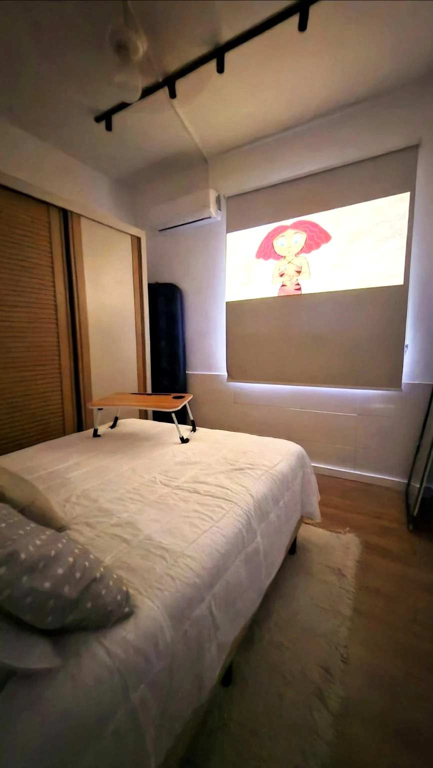 Quarto com ar-condicionado, cama de casal e projeção de filme no telão