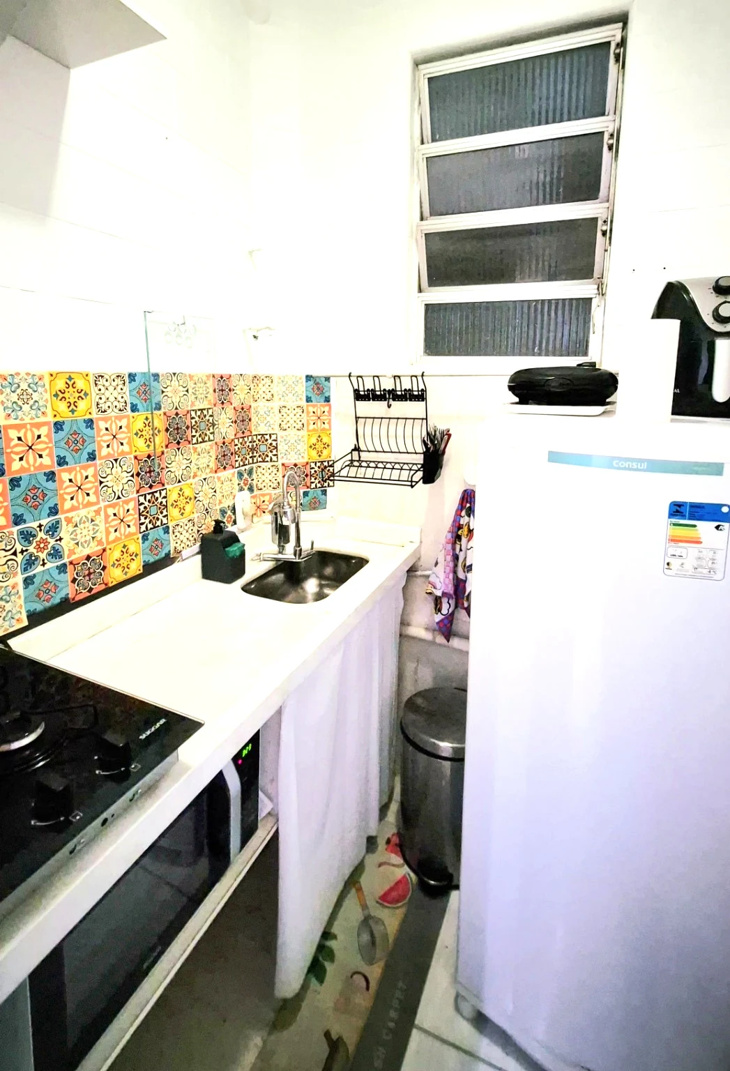 Cozinha real com fogão, micro-ondas, geladeira, air fryer e azulejos coloridos